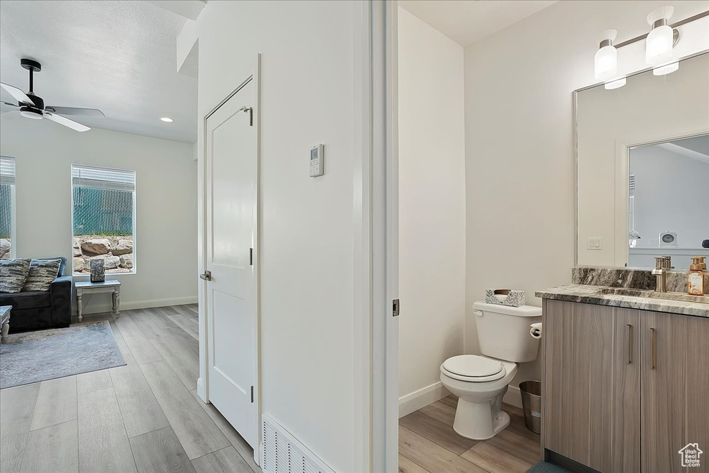 Bathroom with wood finished floors, toilet, a ceiling fan, and visible vents