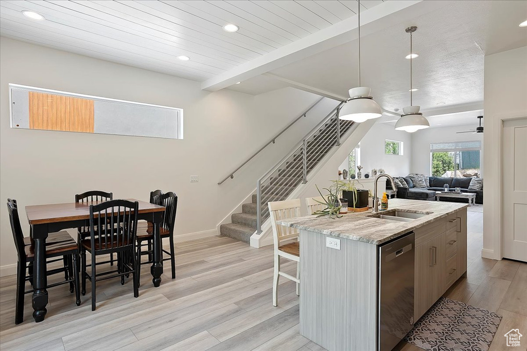 Kitchen featuring recessed lighting, a sink, light wood-type flooring, stainless steel dishwasher, and an island with sink