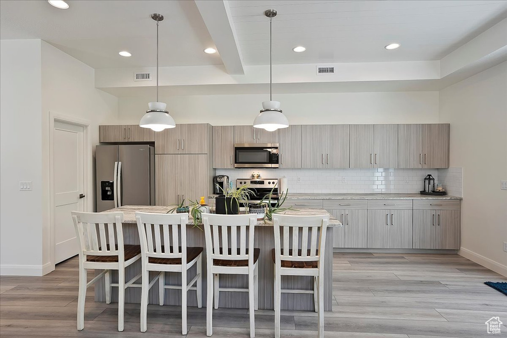 Kitchen featuring appliances with stainless steel finishes, a breakfast bar, visible vents, and baseboards