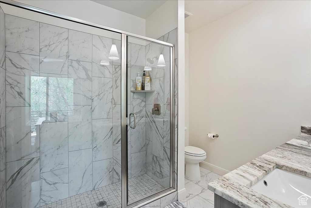 Full bath with vanity, toilet, marble finish floor, and a marble finish shower