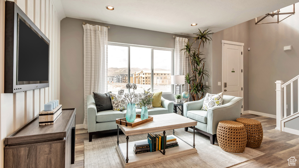 Living room with recessed lighting, stairway, baseboards, light wood-type flooring, and a notable chandelier