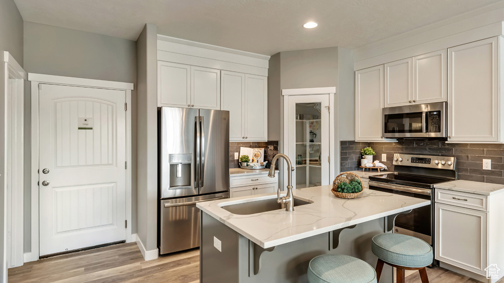 Kitchen featuring tasteful backsplash, light stone countertops, stainless steel appliances, and a sink
