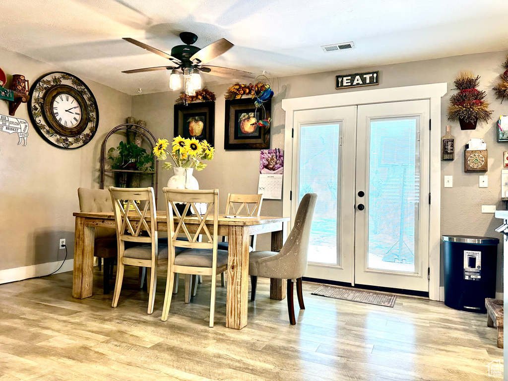 Dining room featuring ceiling fan, visible vents, baseboards, french doors, and wood finished floors