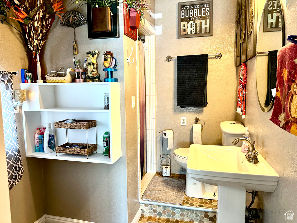 Full bathroom featuring a textured wall, toilet, a stall shower, and baseboards