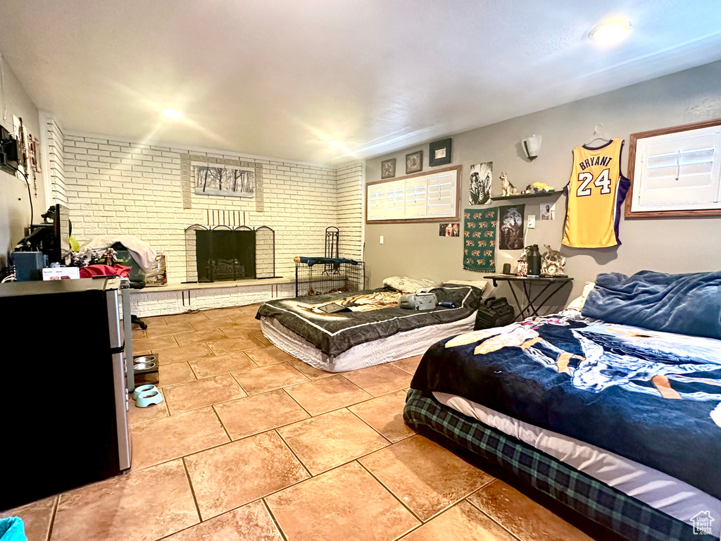 Tiled bedroom with brick wall and a fireplace