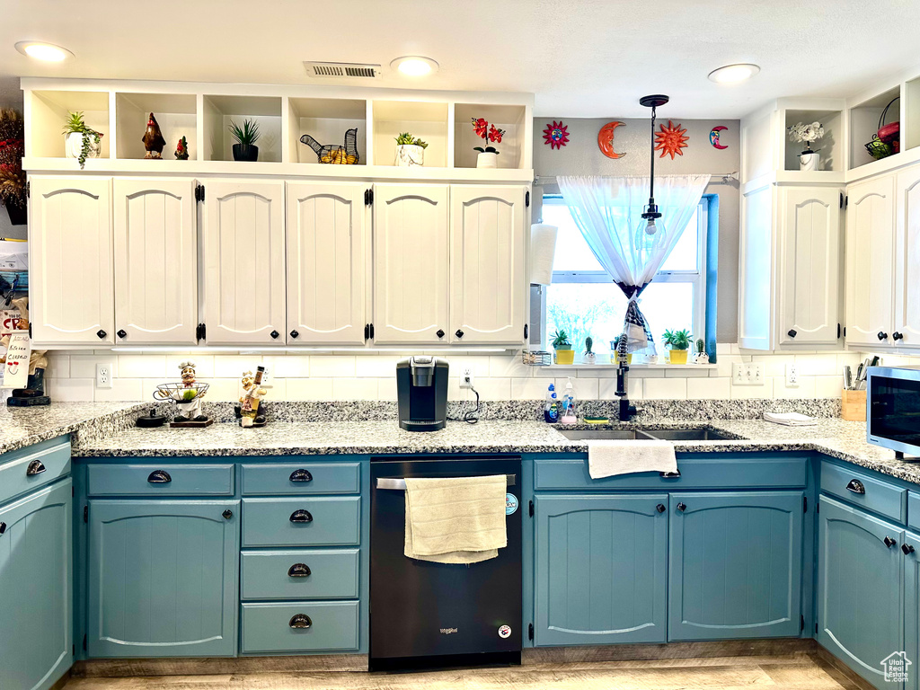 Kitchen featuring a sink, appliances with stainless steel finishes, visible vents, light stone countertops, and decorative light fixtures