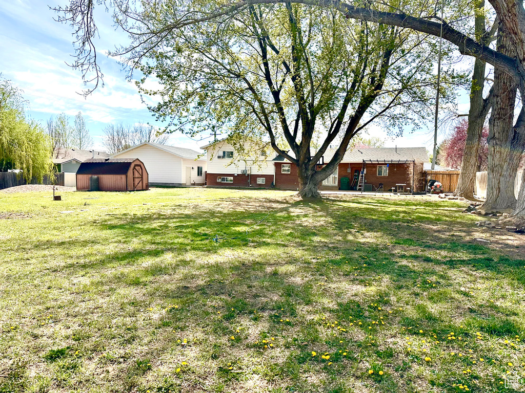 View of yard featuring fence, an outdoor structure, and a storage shed