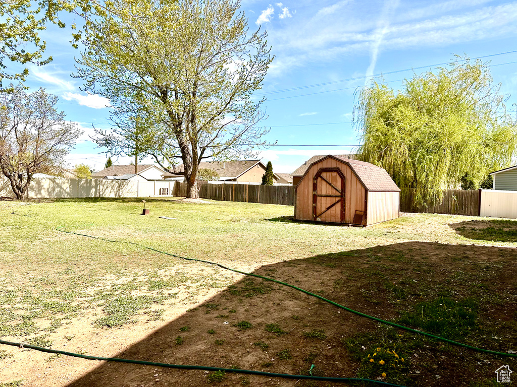 View of yard with a storage unit, a fenced backyard, and an outbuilding