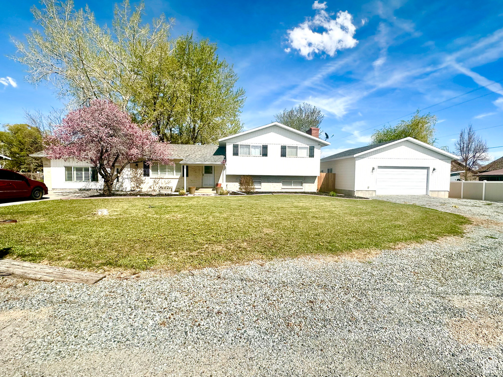 Tri-level home featuring driveway, fence, an attached garage, and a front lawn