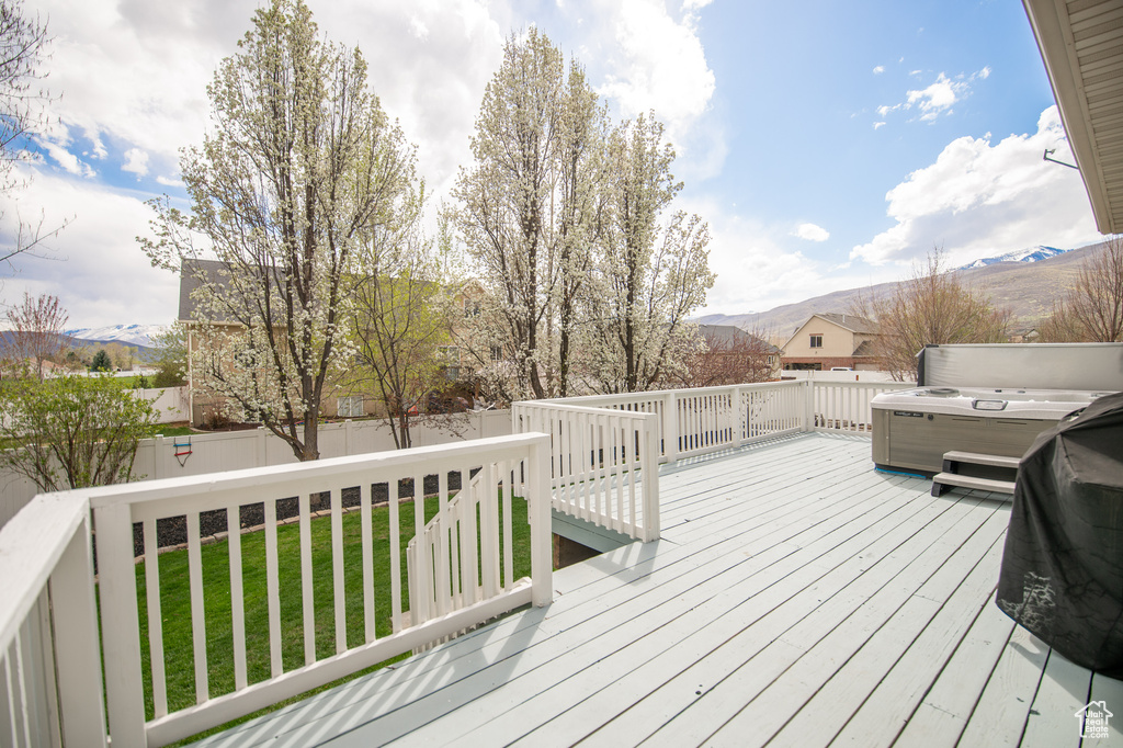 Wooden terrace with a mountain view, a fenced backyard, and a lawn