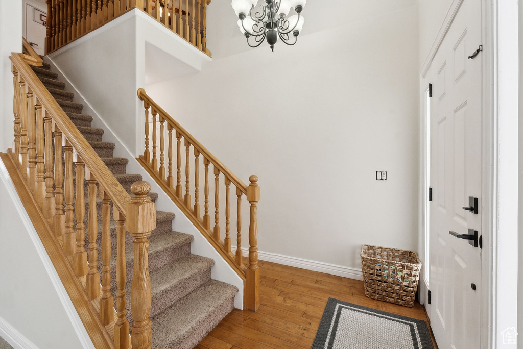 Entryway featuring baseboards, wood finished floors, a high ceiling, stairs, and a notable chandelier