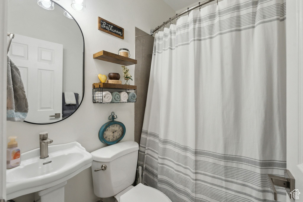 Bathroom with a shower with shower curtain, a sink, and toilet