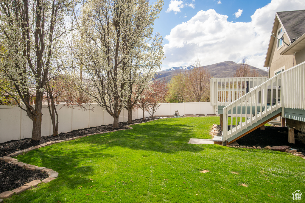 View of yard with a deck with mountain view, stairway, and a fenced backyard