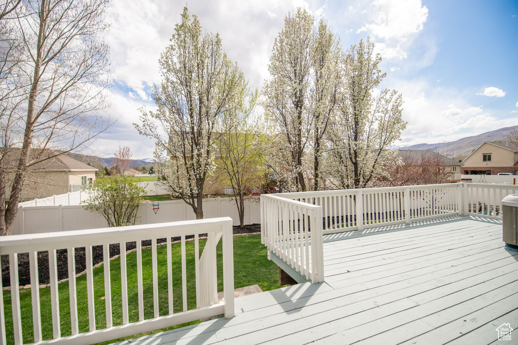 Wooden deck with a lawn, a fenced backyard, and a mountain view