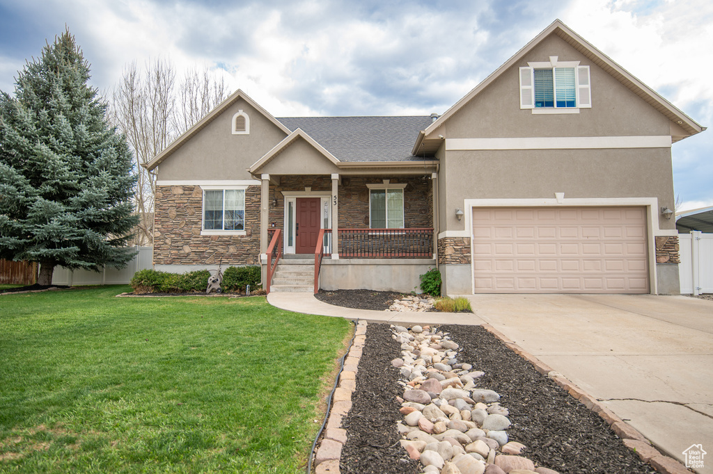 Craftsman inspired home featuring stucco siding, fence, stone siding, a front lawn, and concrete driveway