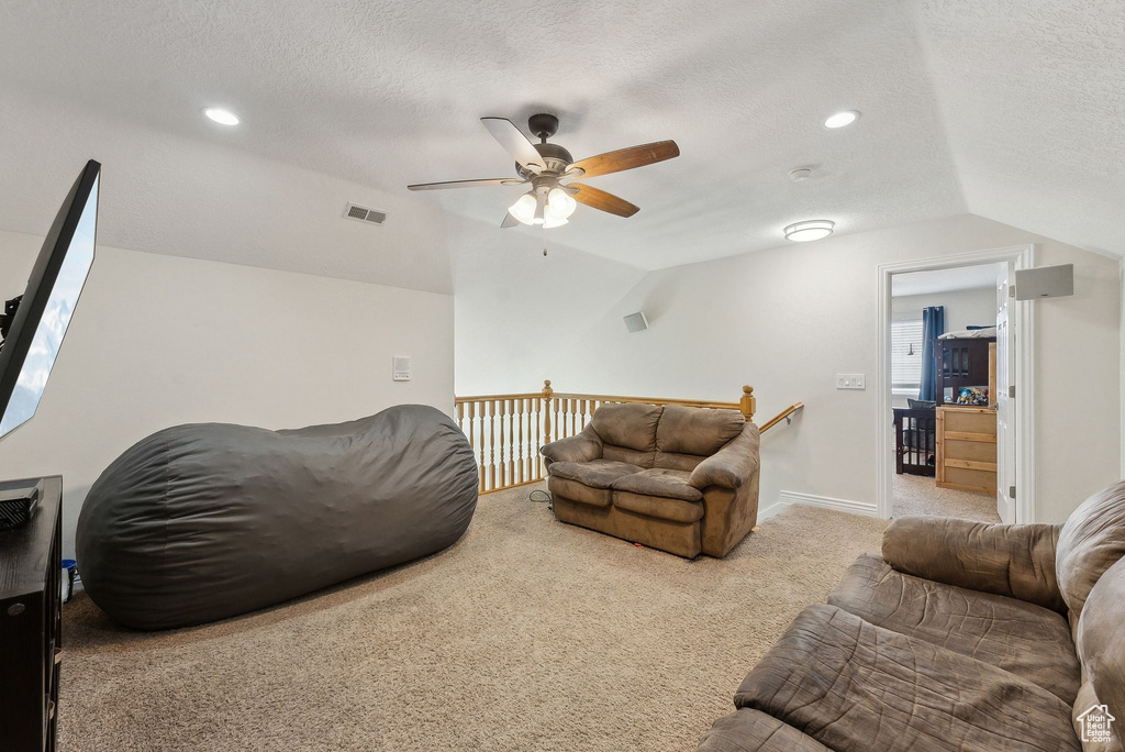 Living area with baseboards, visible vents, lofted ceiling, carpet, and a textured ceiling