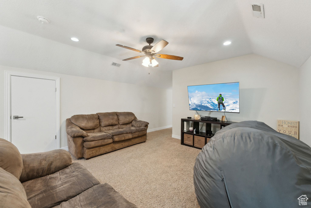 Living room with a ceiling fan, light carpet, vaulted ceiling, and visible vents