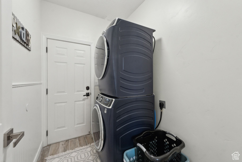Clothes washing area featuring light wood-type flooring, stacked washer / dryer, and laundry area