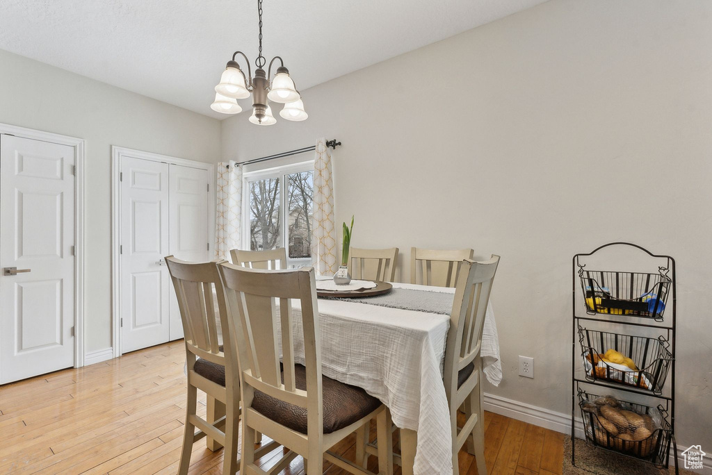 Dining space with a chandelier, light wood finished floors, and baseboards