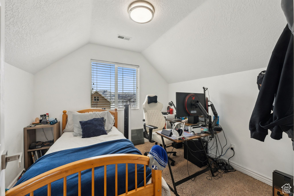 Carpeted bedroom featuring lofted ceiling, baseboards, visible vents, and a textured ceiling