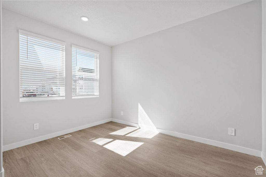 Unfurnished room featuring visible vents, baseboards, and wood finished floors