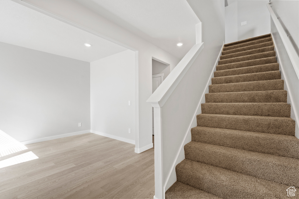 Stairs with recessed lighting, baseboards, and wood finished floors