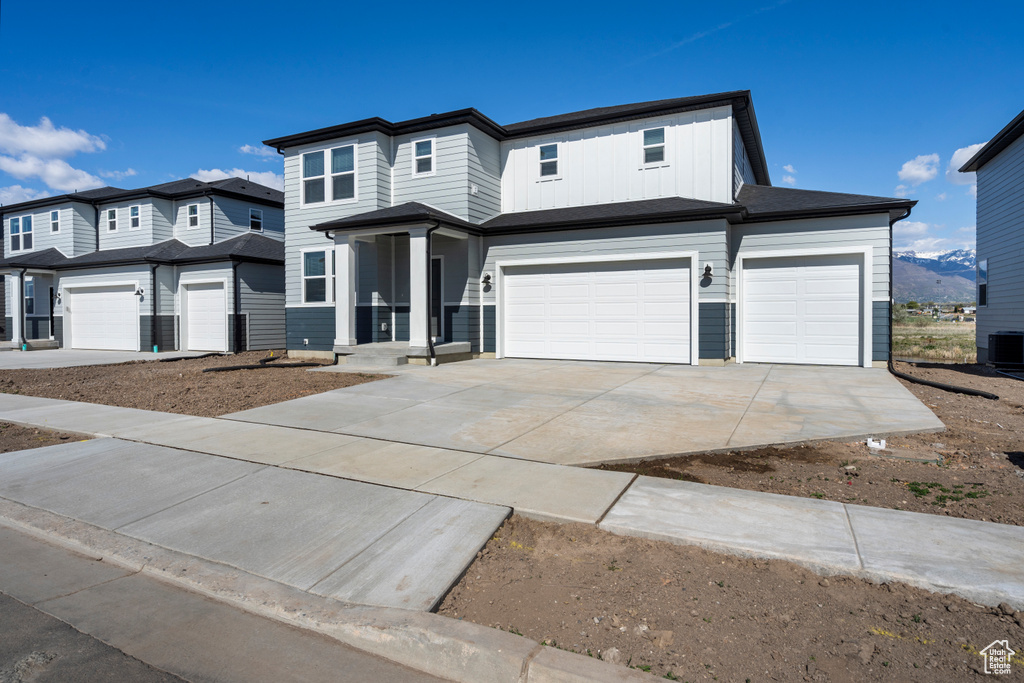 View of front of home featuring a garage, central AC unit, and driveway
