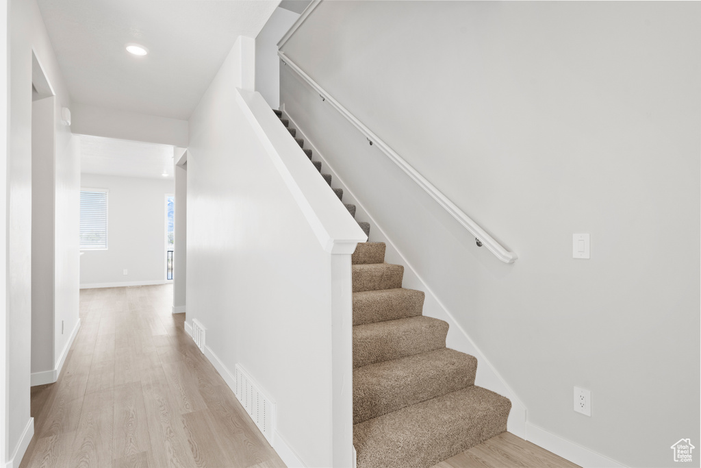 Stairway featuring baseboards, recessed lighting, wood finished floors, and visible vents