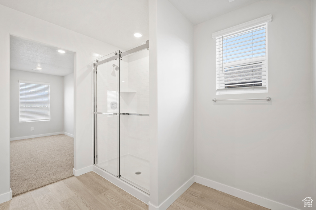 Bathroom with a shower stall, wood finished floors, and plenty of natural light