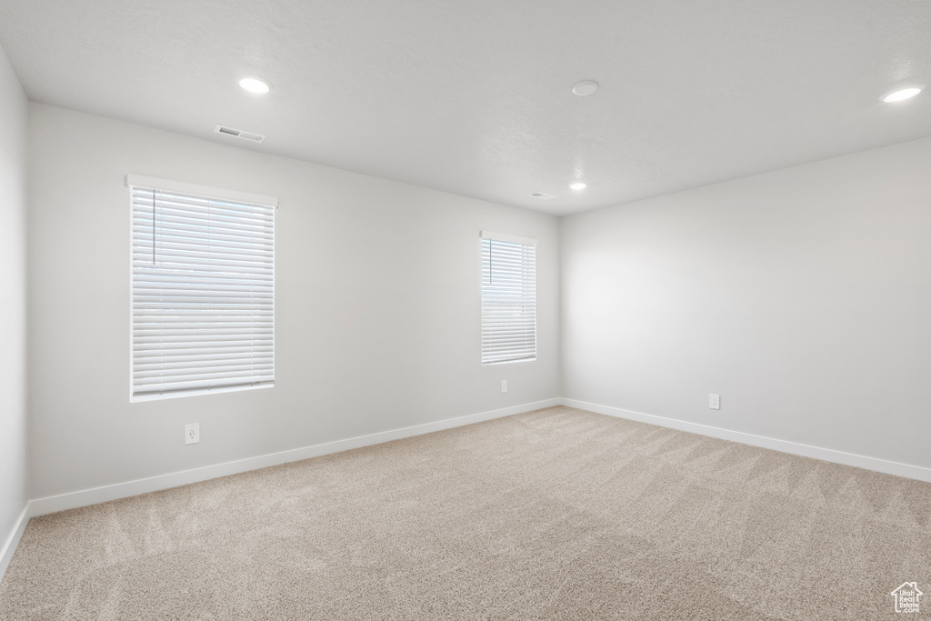 Empty room featuring recessed lighting, light colored carpet, and visible vents