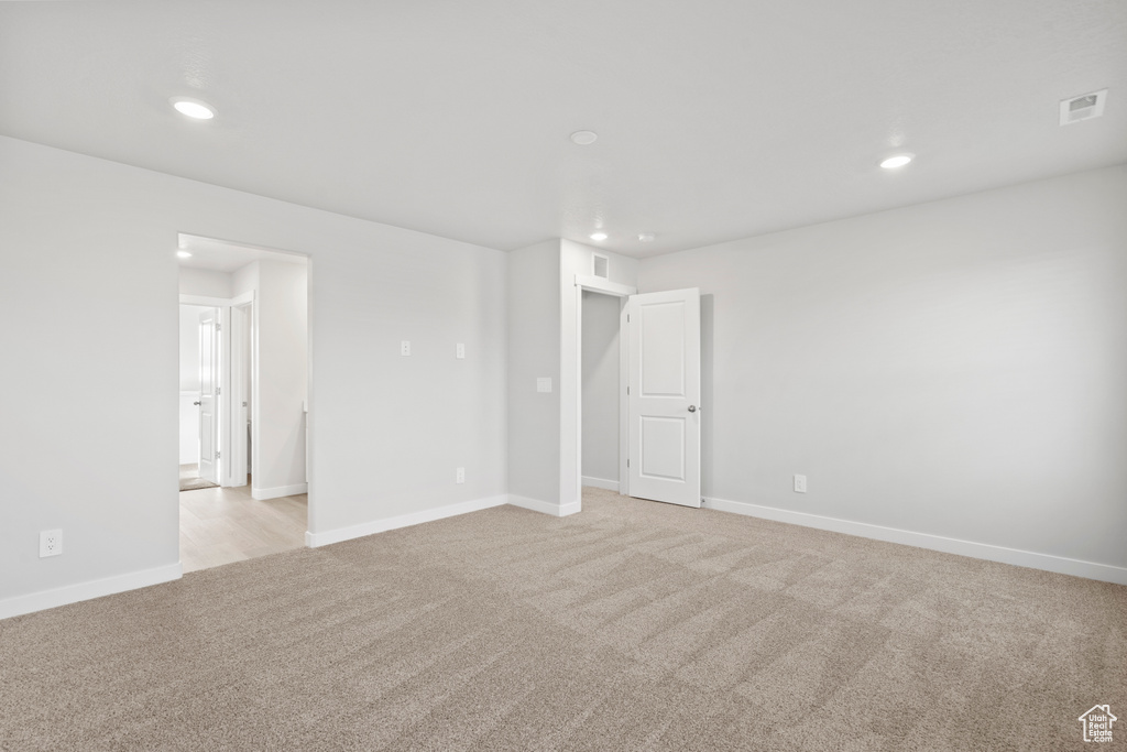 Spare room with recessed lighting, baseboards, light colored carpet, and visible vents