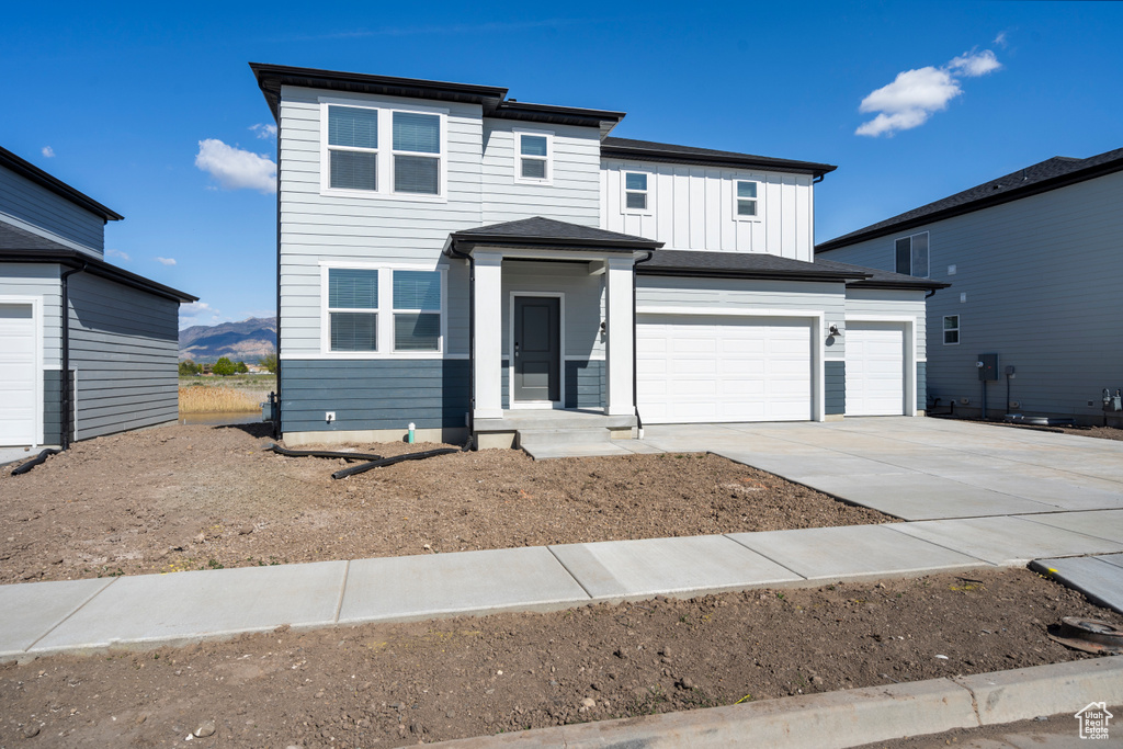 View of front of property with concrete driveway, an attached garage, and board and batten siding