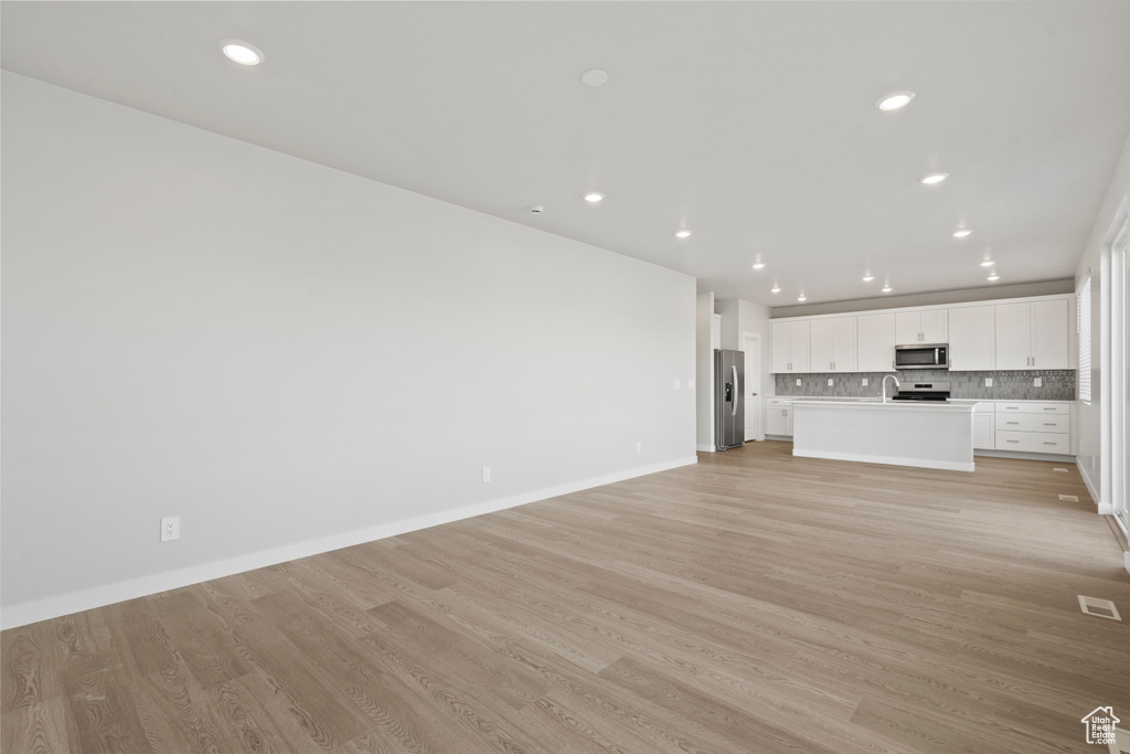 Unfurnished living room featuring recessed lighting, light wood-style floors, baseboards, and visible vents