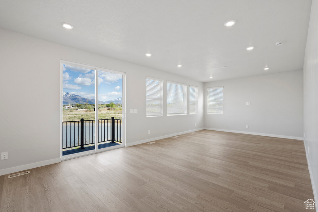 Spare room with light wood-style floors, recessed lighting, baseboards, a water view, and visible vents
