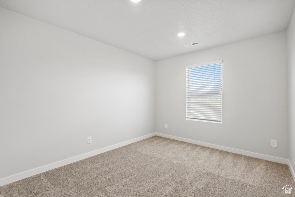 Carpeted empty room featuring baseboards, recessed lighting, and visible vents