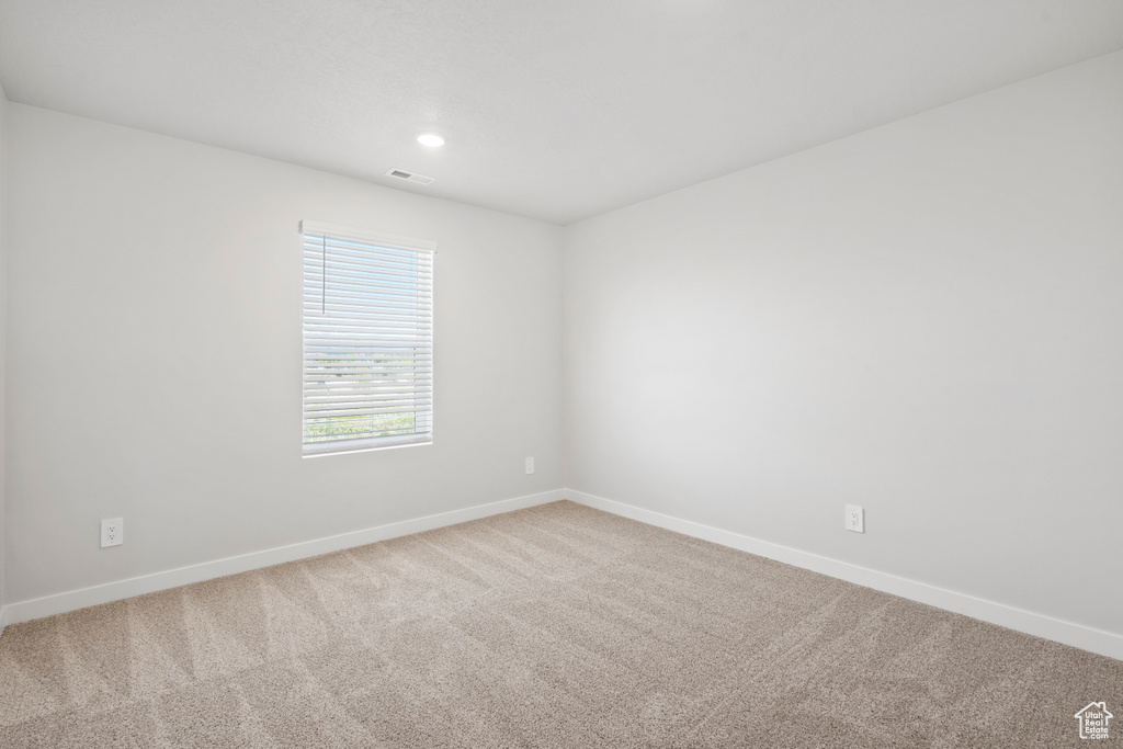 Carpeted empty room featuring baseboards, recessed lighting, and visible vents