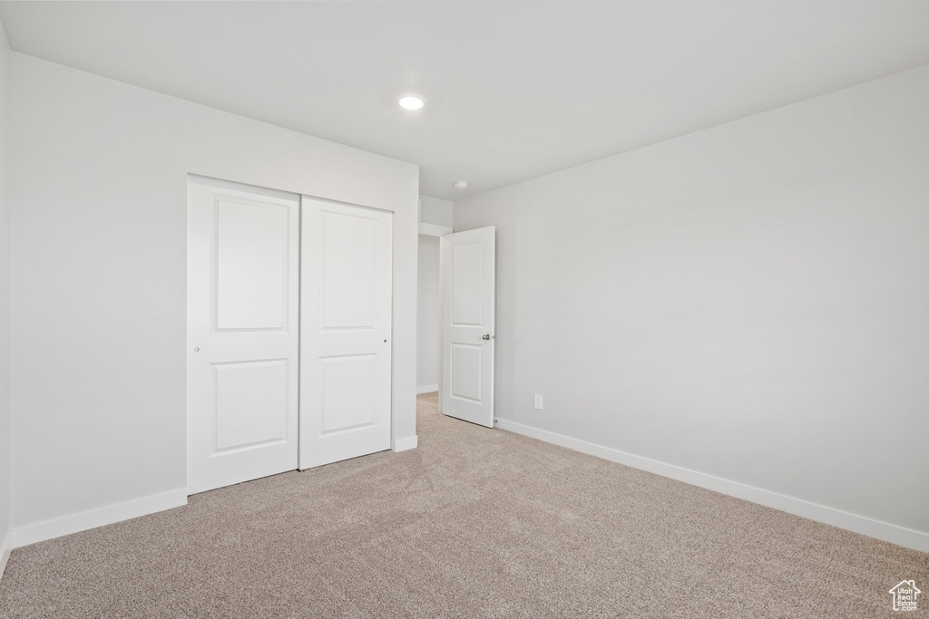 Unfurnished bedroom featuring recessed lighting, baseboards, light carpet, and a closet