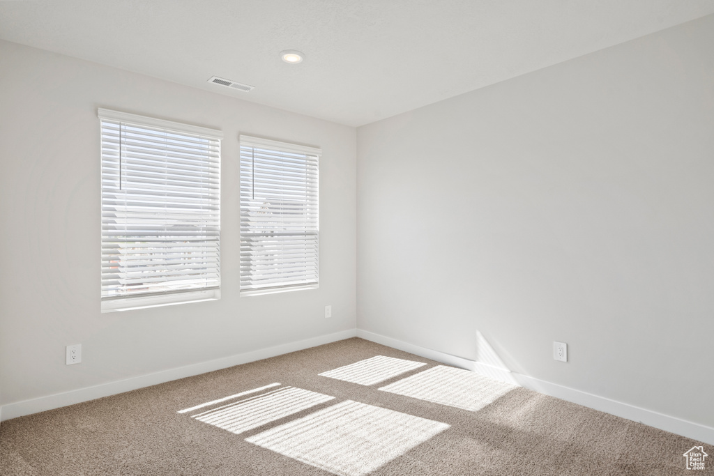 Spare room with visible vents, carpet, and baseboards