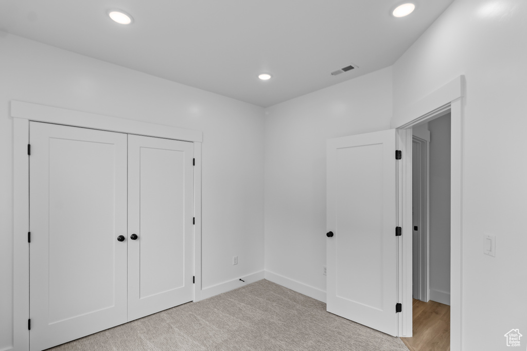 Unfurnished bedroom featuring recessed lighting, light colored carpet, a closet, baseboards, and visible vents