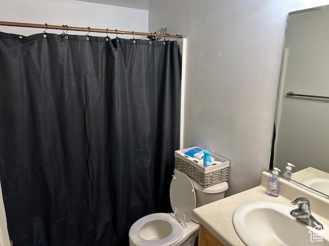 Bathroom featuring toilet, a shower with curtain, and vanity