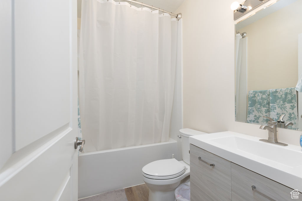 Full bath featuring shower / bathtub combination with curtain, wood finished floors, toilet, and vanity