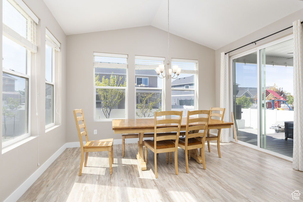 Dining area with an inviting chandelier, light wood finished floors, vaulted ceiling, and baseboards