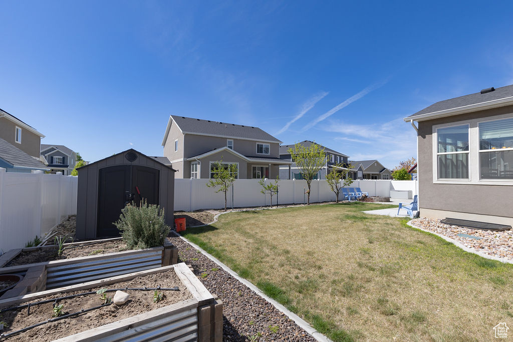 View of yard featuring an outdoor structure, a shed, a vegetable garden, and a fenced backyard