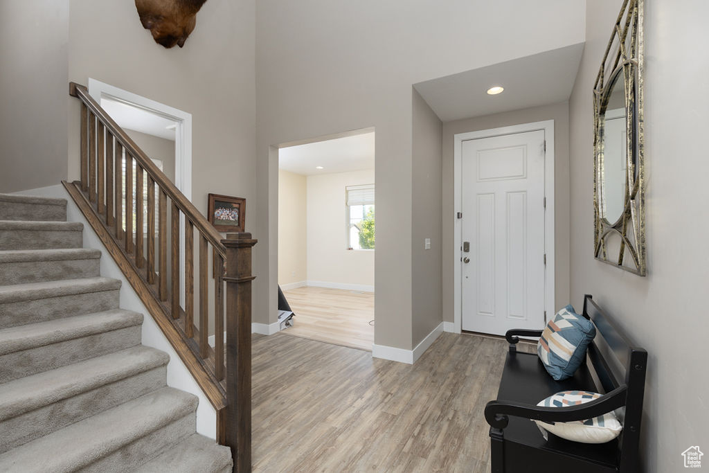 Foyer entrance featuring baseboards, light wood-type flooring, stairway, and recessed lighting