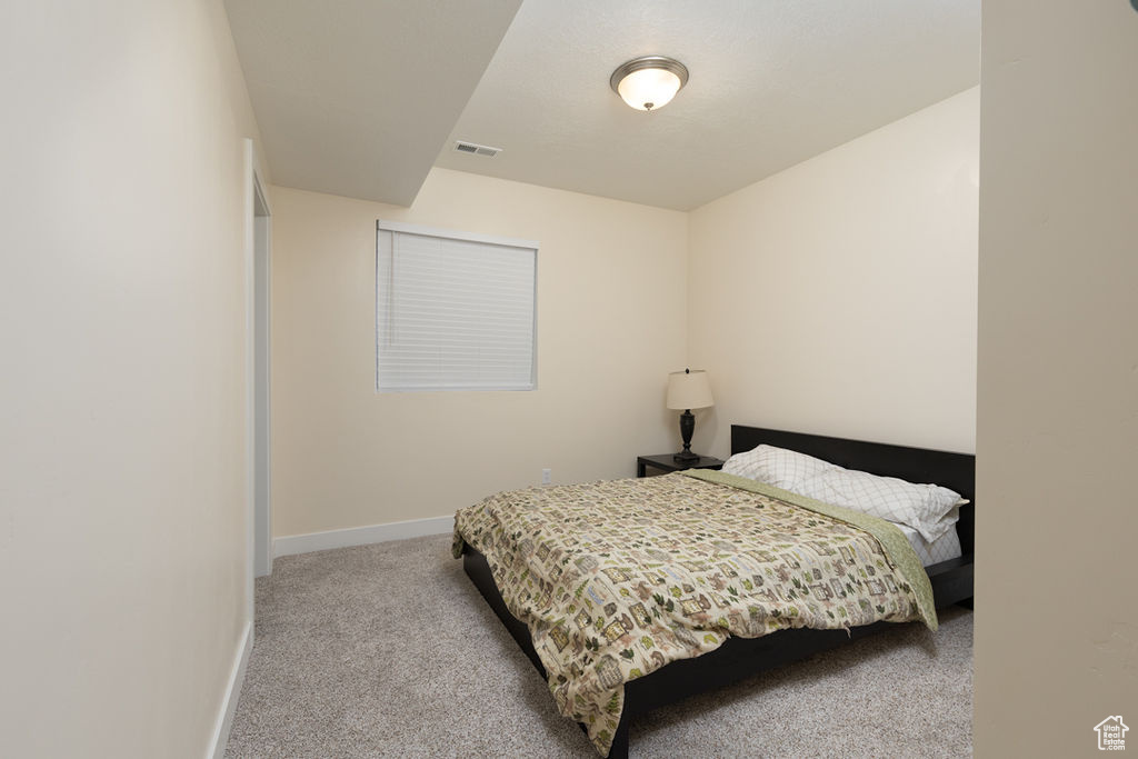 Carpeted bedroom featuring visible vents and baseboards