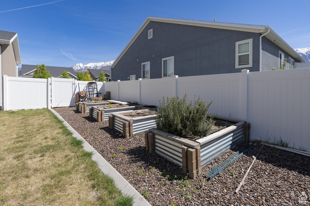 View of yard with a gate, a fenced backyard, and a vegetable garden