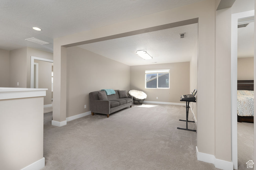 Living room with baseboards, visible vents, and light colored carpet