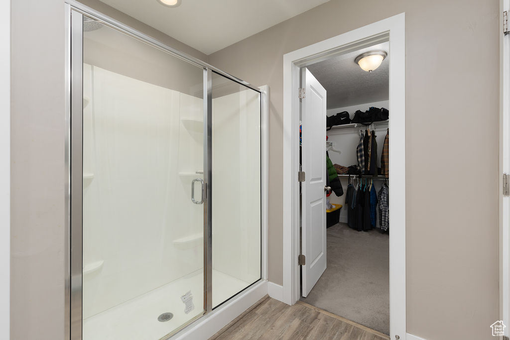 Full bathroom featuring wood finished floors, a spacious closet, a stall shower, and baseboards