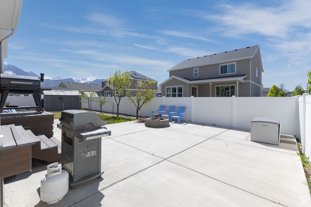 View of patio with an outbuilding, a fenced backyard, a mountain view, a storage unit, and a fire pit