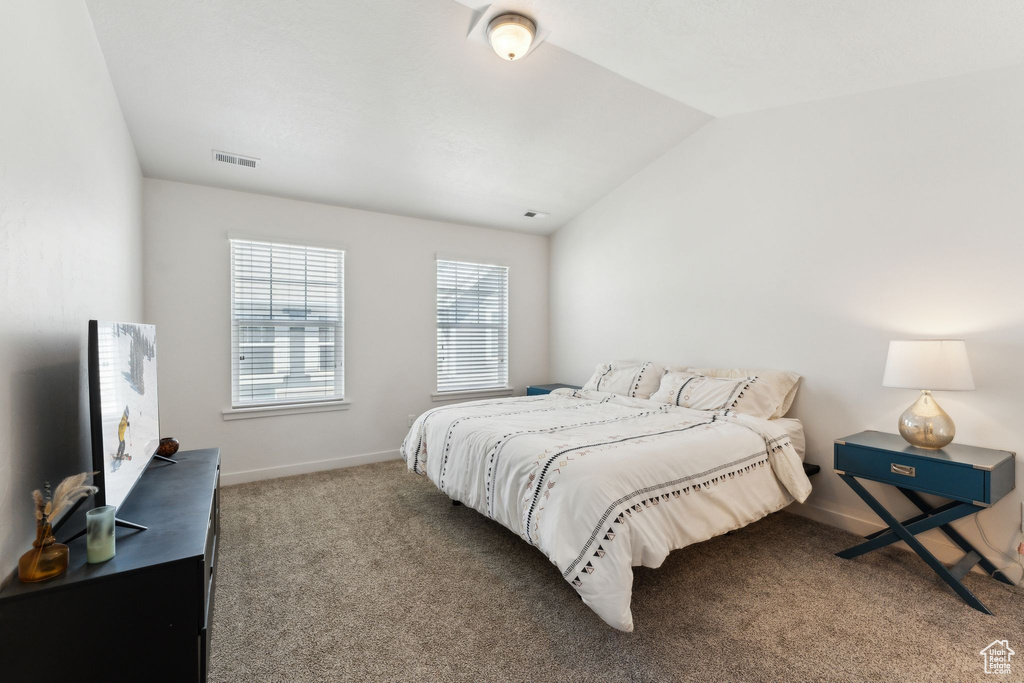 Carpeted bedroom with visible vents, vaulted ceiling, and baseboards